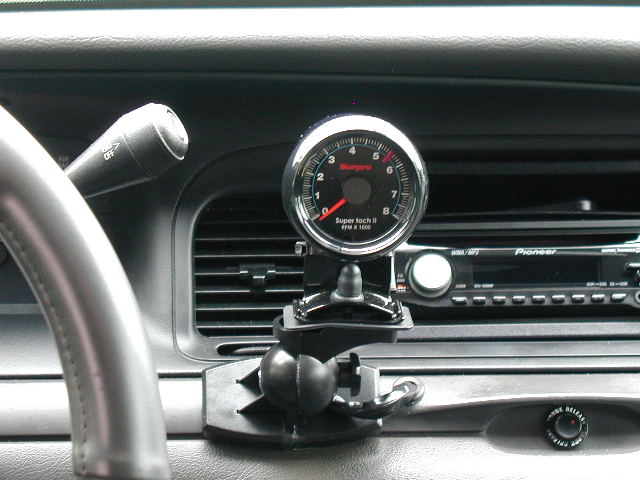 Sunpro Super Tach II tachometer on ball mount in front of dash vents and Pioneer stereo in a black car interior