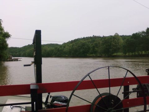 1985 Ford LTD Crown Victoria - A calm river scene with trees lining the banks, viewed from a boat with equipment.