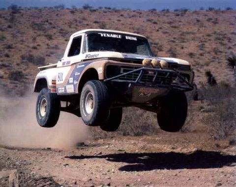 1984 Ford Bronco - This off-road truck, possibly a Ford F-Series from the 1970s, is captured mid-air during a desert race.