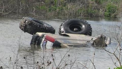 1990 Ford Bronco - Off-road vehicle stuck in water with only part of the body and tires showing.