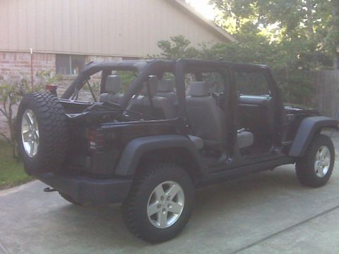 2008 Jeep Wrangler - Black Jeep Wrangler Unlimited four-door JK with all doors removed and the top down, parked in a residential driveway showing the full open-…