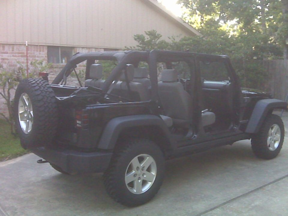 Black Jeep Wrangler Unlimited four-door with doors removed parked in a residential driveway