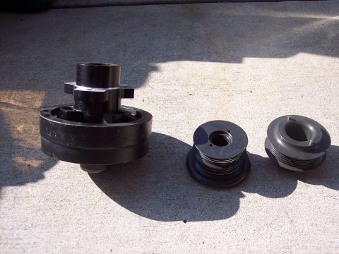 1971 Ford Mustang - Three black automotive pulleys and a hub assembly are laid out on a concrete surface.