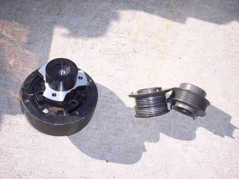 1971 Ford Mustang - A set of engine pulleys, including a crankshaft pulley and two idler pulleys, are displayed on a concrete surface.