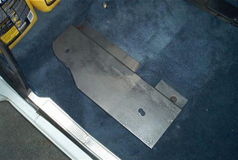 1992 Ford Bronco - A metal plate is placed on the carpeted floor of a vehicle, with a yellow bottle visible in the background.