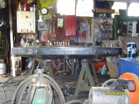 1989 Ford Bronco - A rear bumper is supported by sawhorses in a cluttered garage setting, with tools and equipment visible in the background.