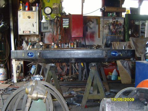 1989 Ford Bronco - Aftermarket rear bumper with integrated blue lights, supported by sawhorses in a cluttered garage.