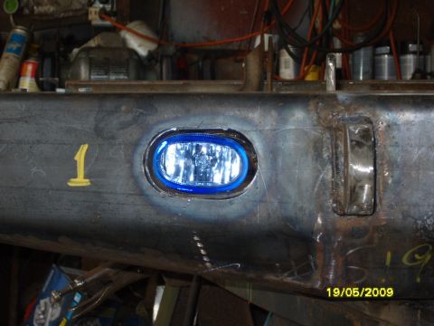 1989 Ford Bronco - A close-up view of a custom metal bumper section, an installed fog light and blue accent trim.