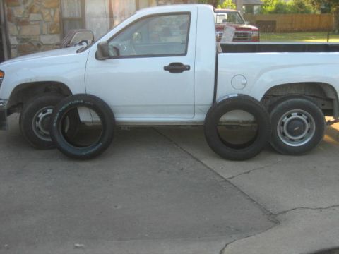 1996 Ford Thunderbird - White pickup truck with tires placed around it on a paved surface.