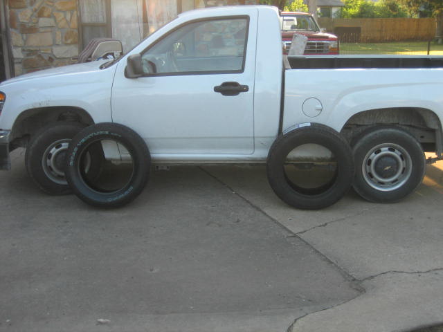 White pickup truck parked on concrete with four tires around it