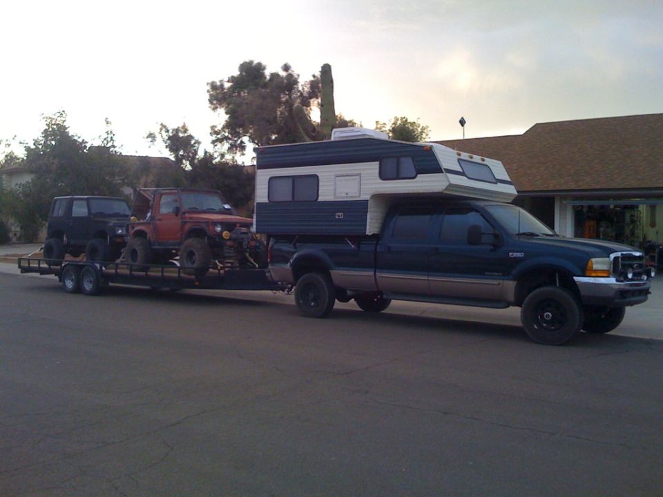 Dark blue pickup truck towing a trailer with two off-road vehicles