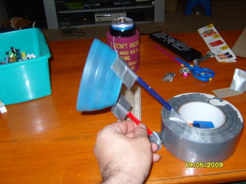 1989 Ford Bronco - A person is holding a blue funnel and a stick, with duct tape and a roll of tape on a wooden table.