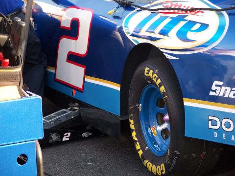 1971 Ford Ranchero - A blue race car with sponsorship decals is being serviced, with a jack visible beneath its side.