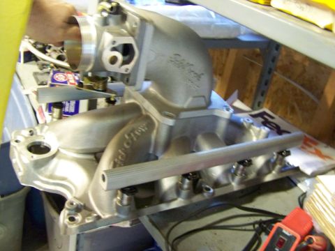 1996 Ford Bronco - An Edelbrock intake manifold is shown with a hand holding the throttle body assembly.