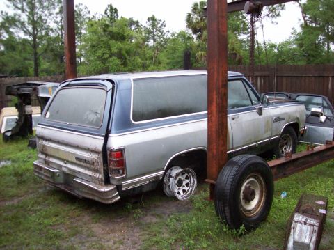 1988 Dodge Power Ram - Rear view of a 1988 Dodge Ramcharger SUV in an outdoor setting, missing a wheel.