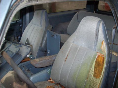 1988 Dodge Power Ram - The interior of the vehicle shows significant wear and tear on the seats and a cluttered floor.