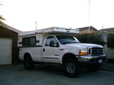 2000 Ford F-250 - Pickup truck with a camper shell parked in front of a garage.