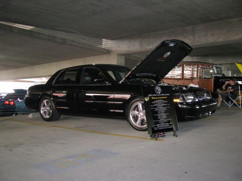 2003 Mercury Marauder - A black 2003 Mercury Marauder is displayed with its hood open at a car show, an information board detailing its specifications.