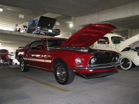 2003 Mercury Marauder - A red 1969 Ford Mustang Mach 1 is displayed with its hood open at a car show.