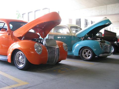 2003 Mercury Marauder - Two vintage cars, one orange and one blue, are displayed with their hoods open at a car show.