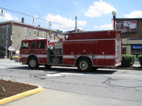 2003 Mercury Marauder - A red fire truck is parked on the side of the road in front of buildings and bushes.