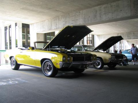 2003 Mercury Marauder - Two vintage convertibles, a yellow and a tan model, are parked with their hoods open, displaying their engines.