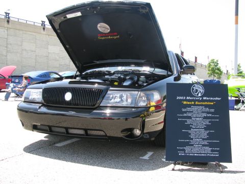 2003 Mercury Marauder - A black 2003 Mercury Marauder is displayed with its hood open at a car show, alongside a descriptive sign.