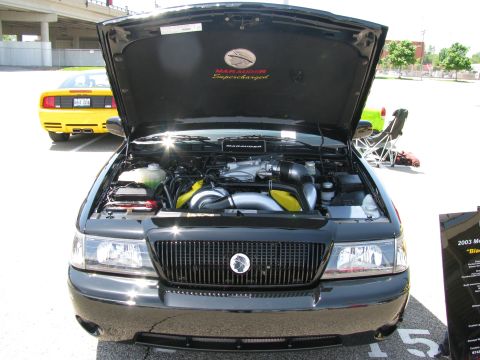2003 Mercury Marauder - A black 2003 Mercury Marauder is displayed with its hood open, revealing the supercharged engine. Another car is visible in the background.