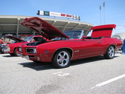 2003 Mercury Marauder - Two red cars are parked at an outdoor event with stadium seating in the background.