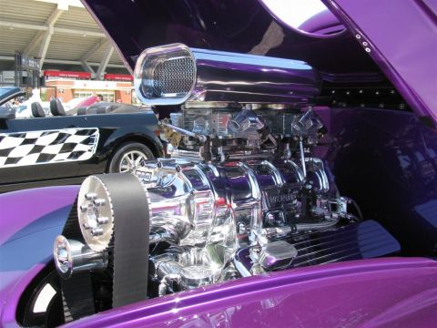 2003 Mercury Marauder - Custom purple hot rod engine with a chrome supercharger and dual carburetors is displayed at a car show. A black convertible with a checker…