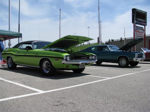 2003 Mercury Marauder - Two classic muscle cars, a lime green model and a dark teal one, are displayed with their hoods open at a car show.