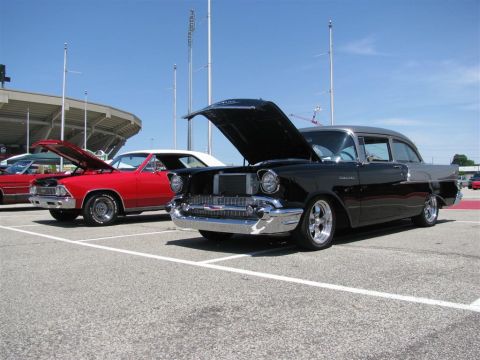 2003 Mercury Marauder - Two classic cars are parked in a lot under a bright blue sky, with a stadium in the background.