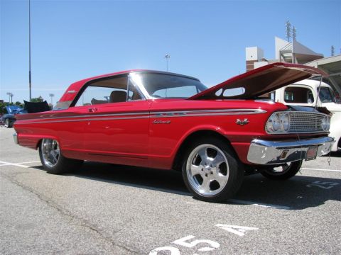2003 Mercury Marauder - A bright red 1963 Ford Fairlane is displayed with its hood up at an outdoor event.
