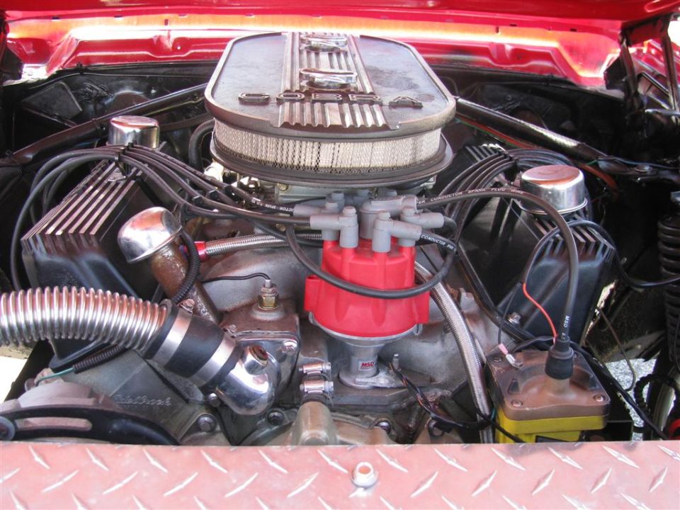 Engine bay with a chrome air cleaner, red distributor cap, and ribbed metal intake hose
