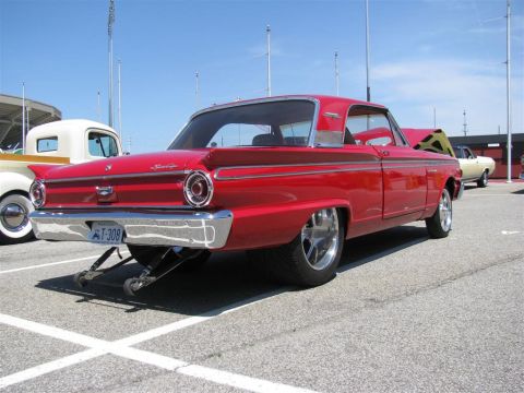 2003 Mercury Marauder - A red 1960s coupe with custom wheels and lowered suspension is shown from the rear at a car show.