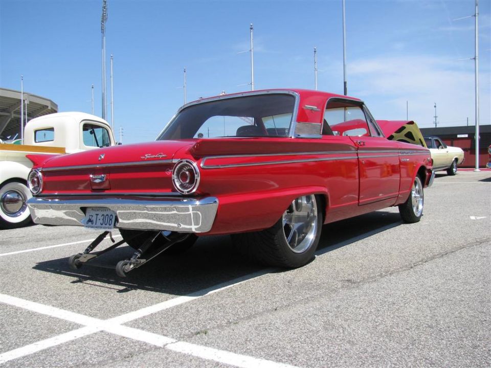 Red 1960s coupe with custom wheels and lowered suspension, rear view