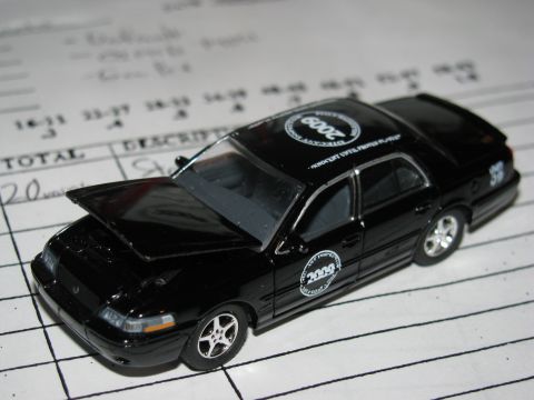 2003 Mercury Marauder - This black toy car features "2003" and "2009" decals and has its hood open, resting on a paper with handwritten notes.