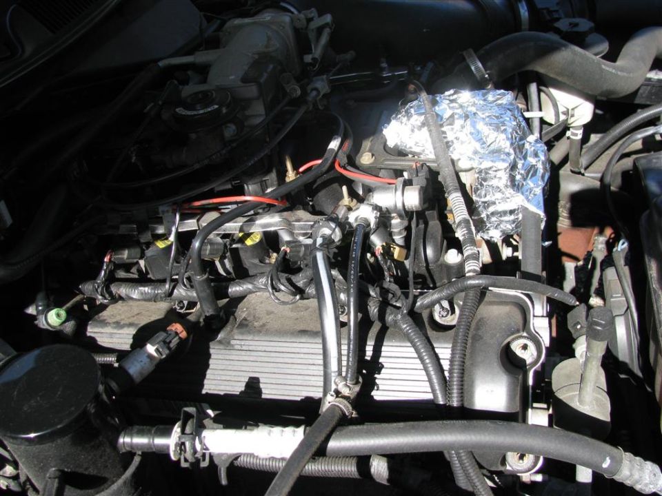 V8 engine bay mid-teardown with intake removed and foil covering open ports