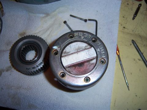 1979 Ford F-150 - A disassembled manual locking hub and a gear are laid out on a surface, with tools nearby.
