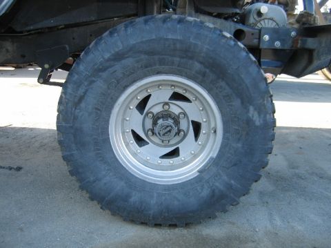 1962 Toyota Land Cruiser - A close-up view of a vehicle's tire and wheel assembly, showing off-road tread and a multi-spoke rim.