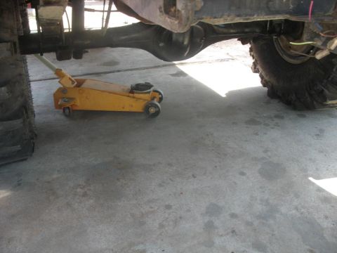 1987 Ford Bronco - Undercarriage view of a vehicle being supported by a floor jack.