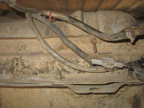 1987 Ford Bronco - Close-up of vehicle undercarriage showing fuel lines and a wiring harness connected to the fuel pump assembly.
