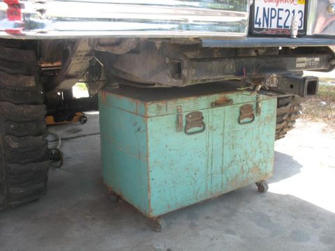 1987 Ford Bronco - A toolbox is placed under the rear of a vehicle, obscuring the fuel pump area.