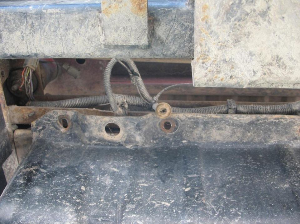 Truck frame rail bolt holes with loom-wrapped wiring harness and connector