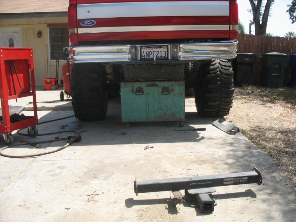 Rear of lifted red Ford truck on a toolbox with removed receiver hitch on the driveway