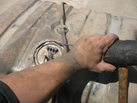 1987 Ford Bronco - Close-up of a fuel tank assembly with a hand gripping a pipe wrench.