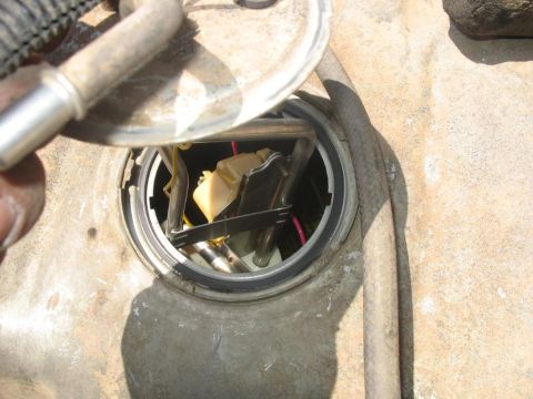 1987 Ford Bronco - The fuel pump assembly is visible inside the fuel tank opening, with a hand reaching in to hold a fuel line.