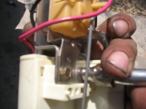 1987 Ford Bronco - Close-up view of a fuel pump assembly, showing a pink wire and metal bracket being held.