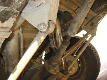 1984 Ford Bronco - The photo shows the complex undercarriage of a vehicle, focusing on suspension and drivetrain parts.