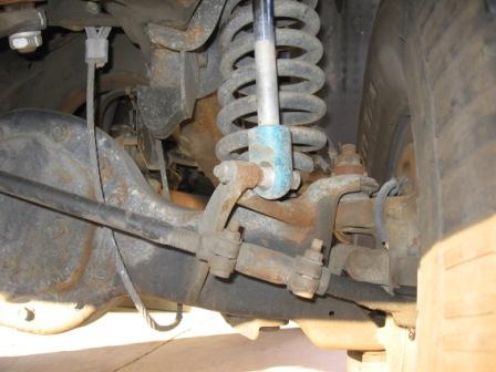 1984 Ford Bronco - Close-up view of the front suspension and axle components, including a coil spring and shock absorber.